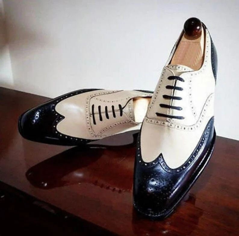 Pair of black and cream dress shoes on a wooden surface