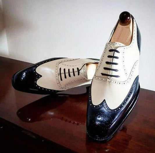 Pair of black and cream dress shoes on a wooden surface