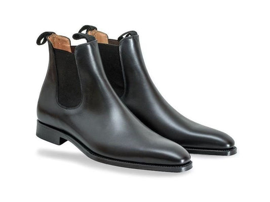 Pair of black leather Chelsea boots on a white background