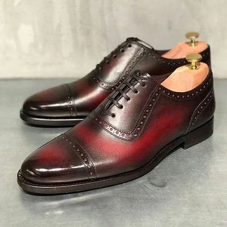 Pair of brown leather dress shoes on a gray surface with a light gray background
