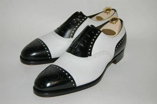 Pair of black and white dress shoes on a light gray background