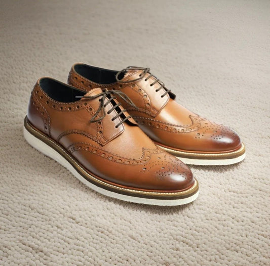 Pair of brown /tan leather dress shoes on a textured surface