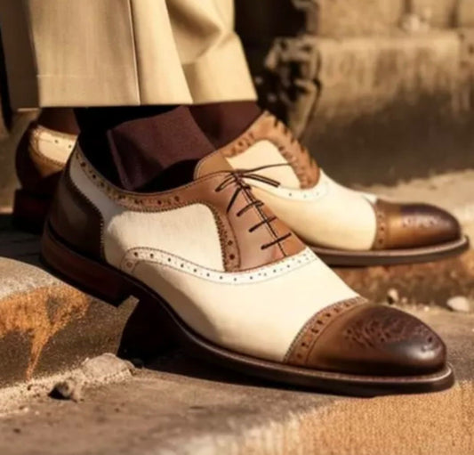 Pair of brown and cream dress shoes on a textured surface