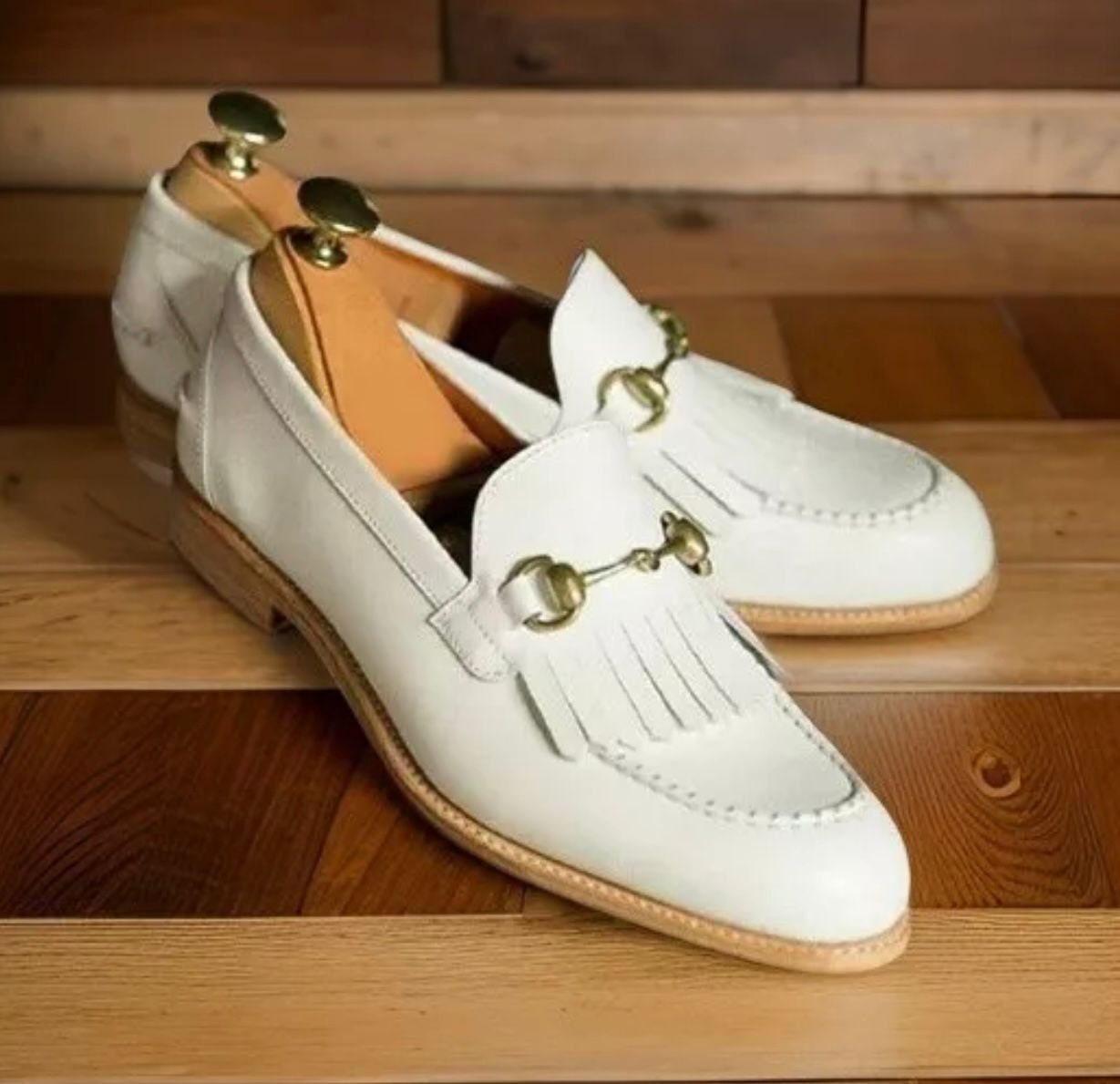 White loafers with gold accents on a wooden surface