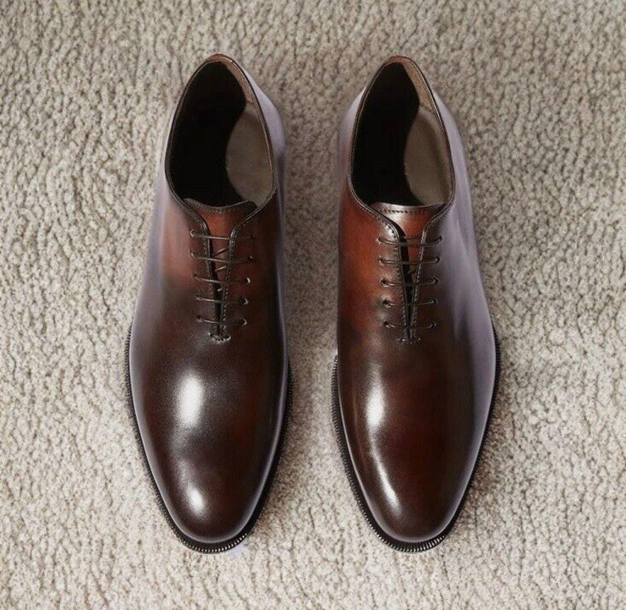 Pair of brown dress shoes on a beige carpet