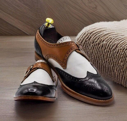 Pair of black, white, and brown dress shoes on a wooden surface.
