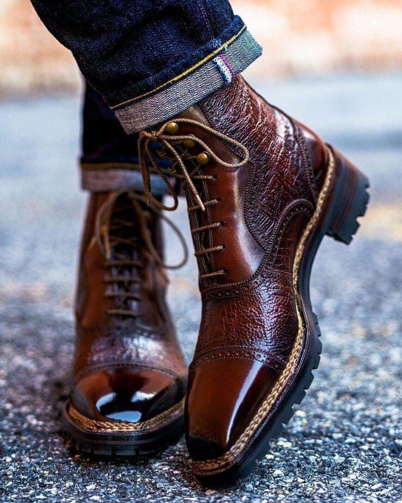 Brown leather boots with crocodile texture worn by a person on a blurred background