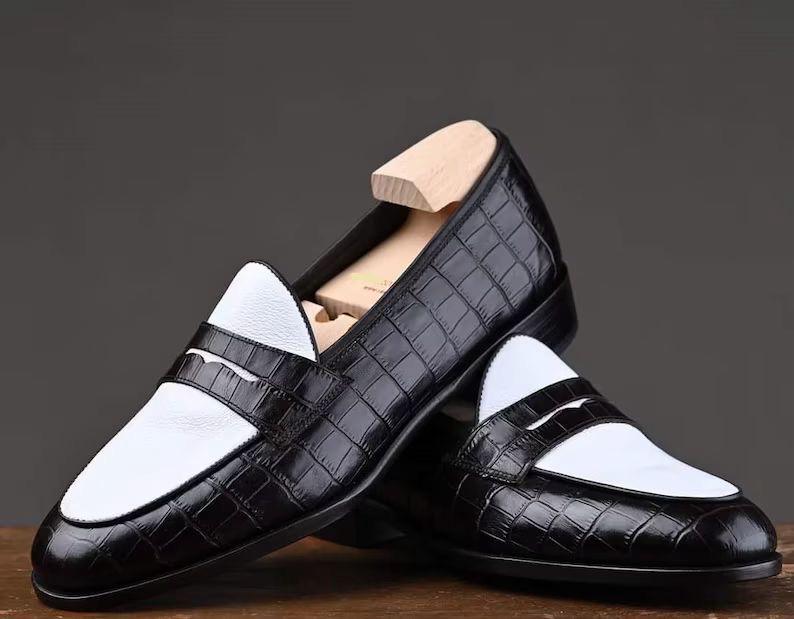 Black and white loafers on a wooden surface with a dark background