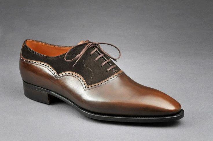 Brown leather and suede dress shoe on a gray background