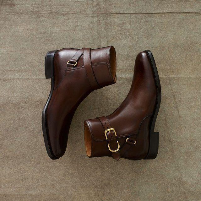 Pair of brown leather boots with buckles on a textured brown background