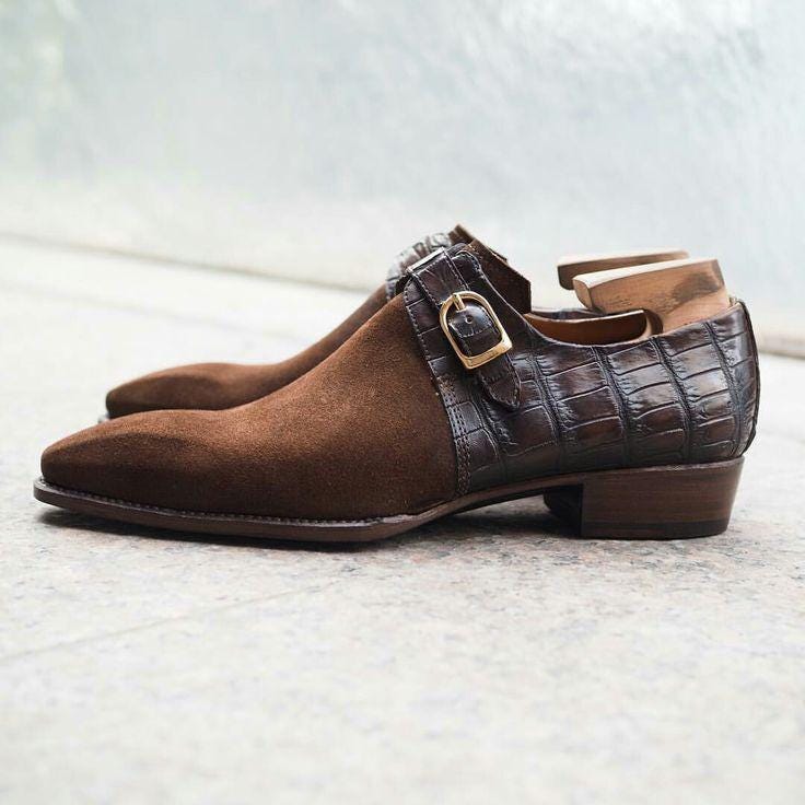Brown suede shoes with a crocodile pattern strap on a light gray background