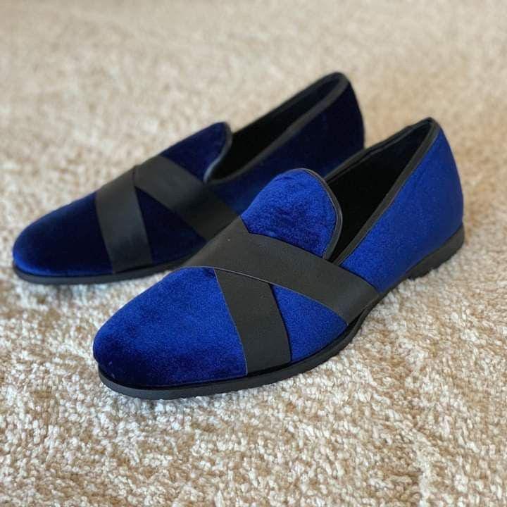 Pair of blue loafers with black straps on a beige carpet