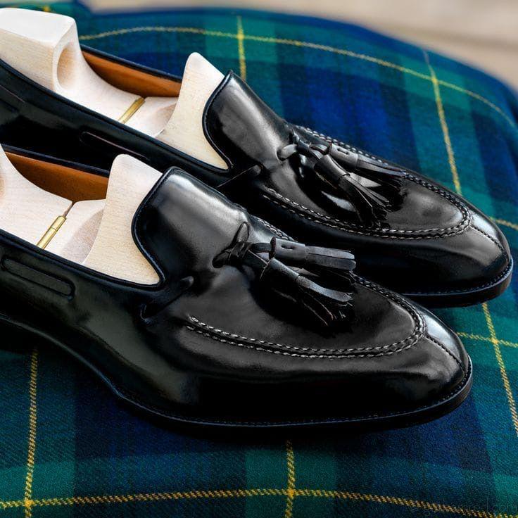 Black loafers with tassels on a plaid fabric background
