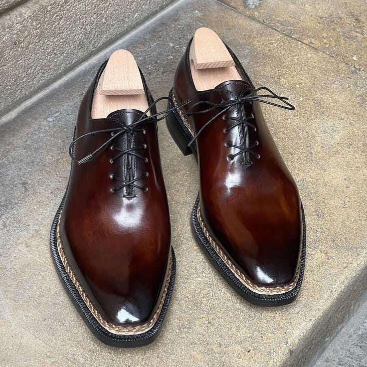 Pair of brown leather dress shoes on a concrete surface
