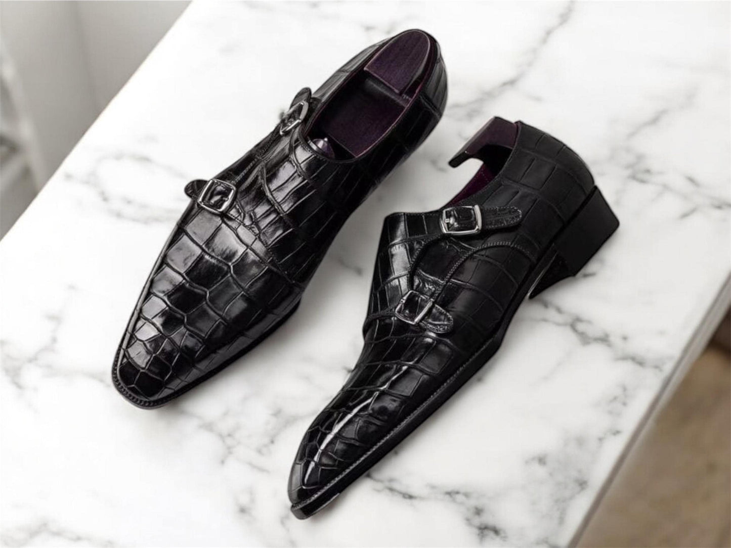 Black crocodile-patterned shoes on a marble surface