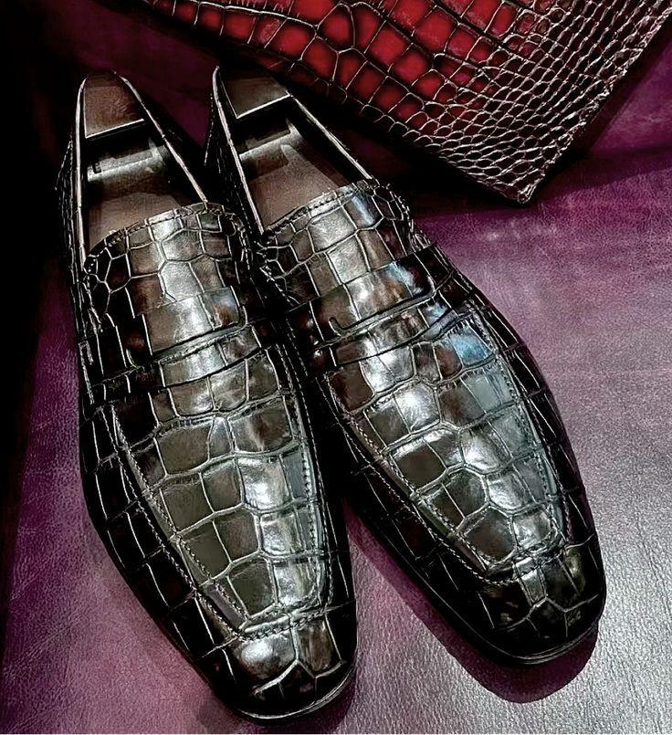 brown loafers on a purple surface with a textured red bag in the background