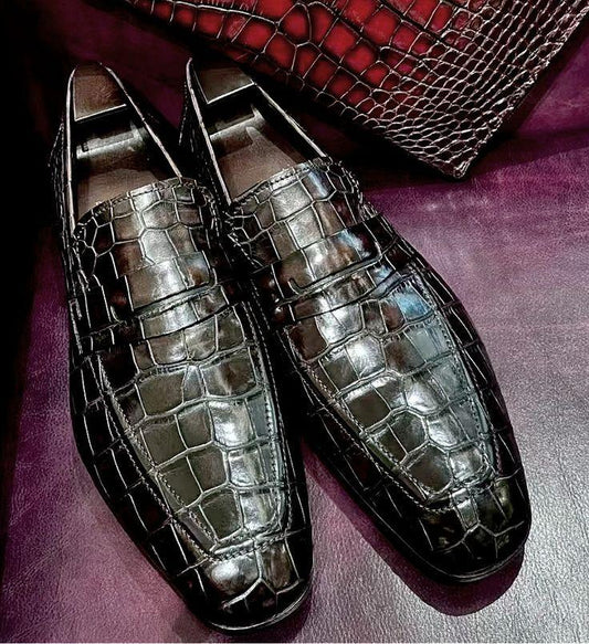 brown loafers on a purple surface with a textured red bag in the background