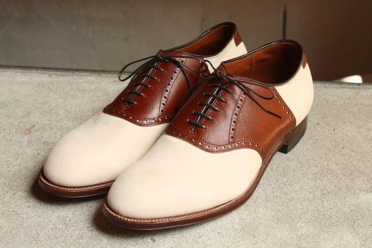 Pair of brown and white dress shoes on a concrete floor.