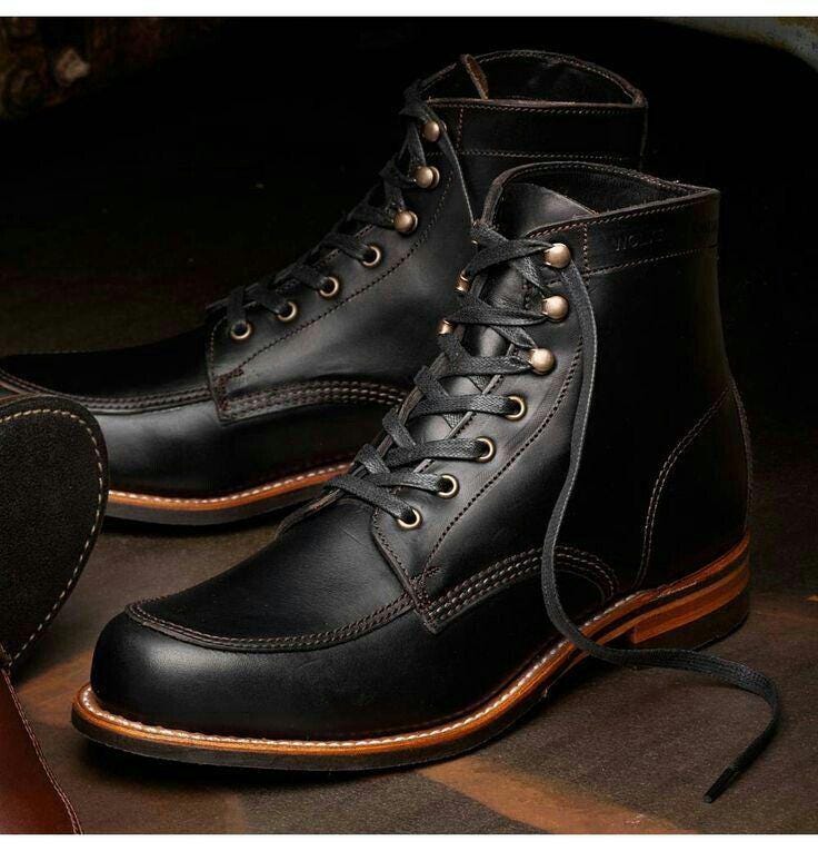 Black leather boots with brown soles on a dark background