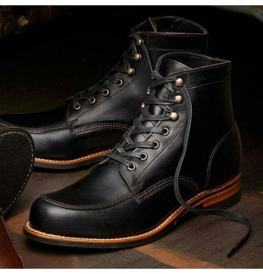 Black leather boots with brown soles on a dark background