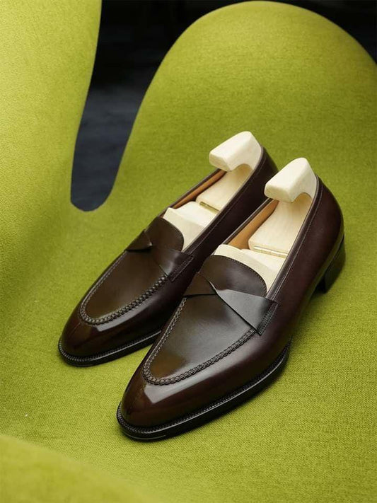 Brown loafers with black soles on a green surface