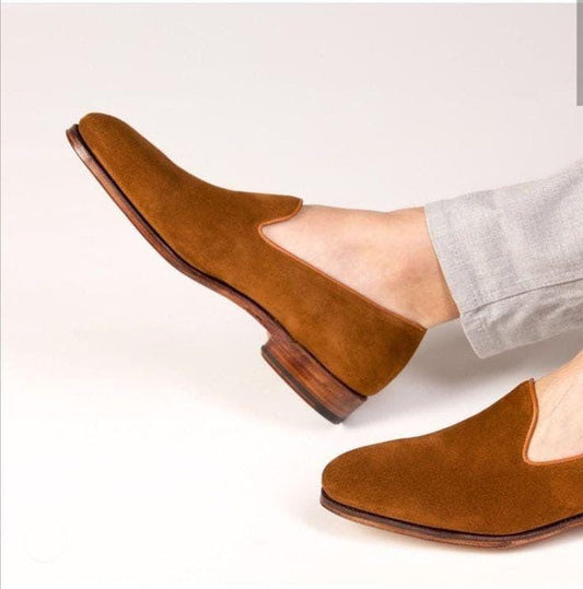 Brown suede shoes worn with light gray pants on a white background