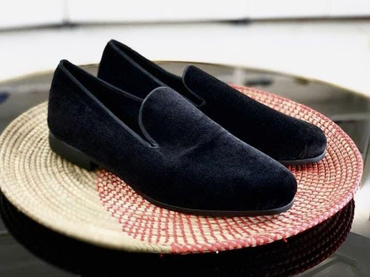 Pair of black suede loafers on a woven mat