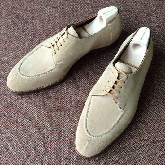Pair of cream beige suede shoes on a textured brown surface
