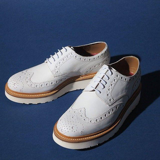 White leather shoes with brown lining and white sole on a blue background